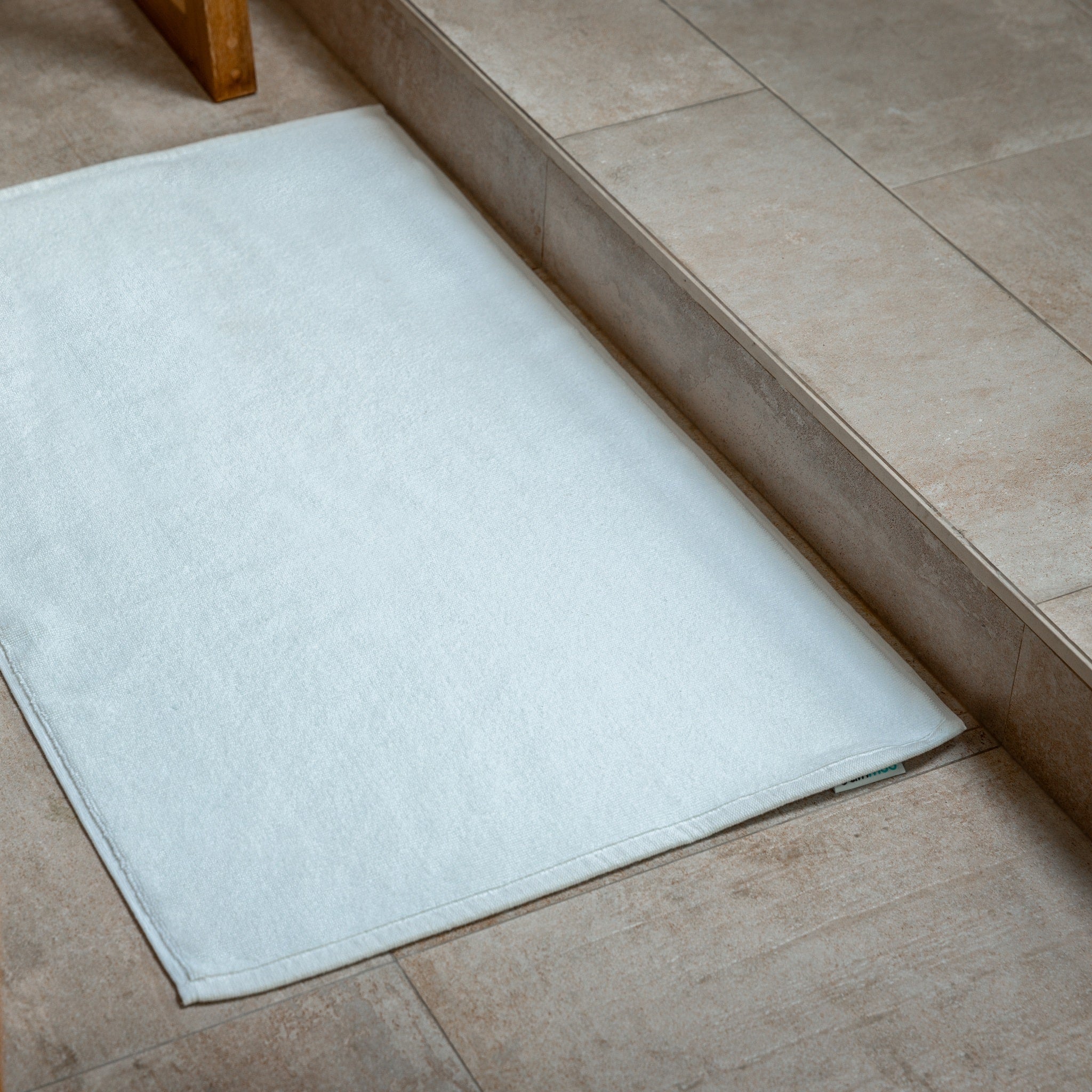 White bath mat on a tiled bathroom floor