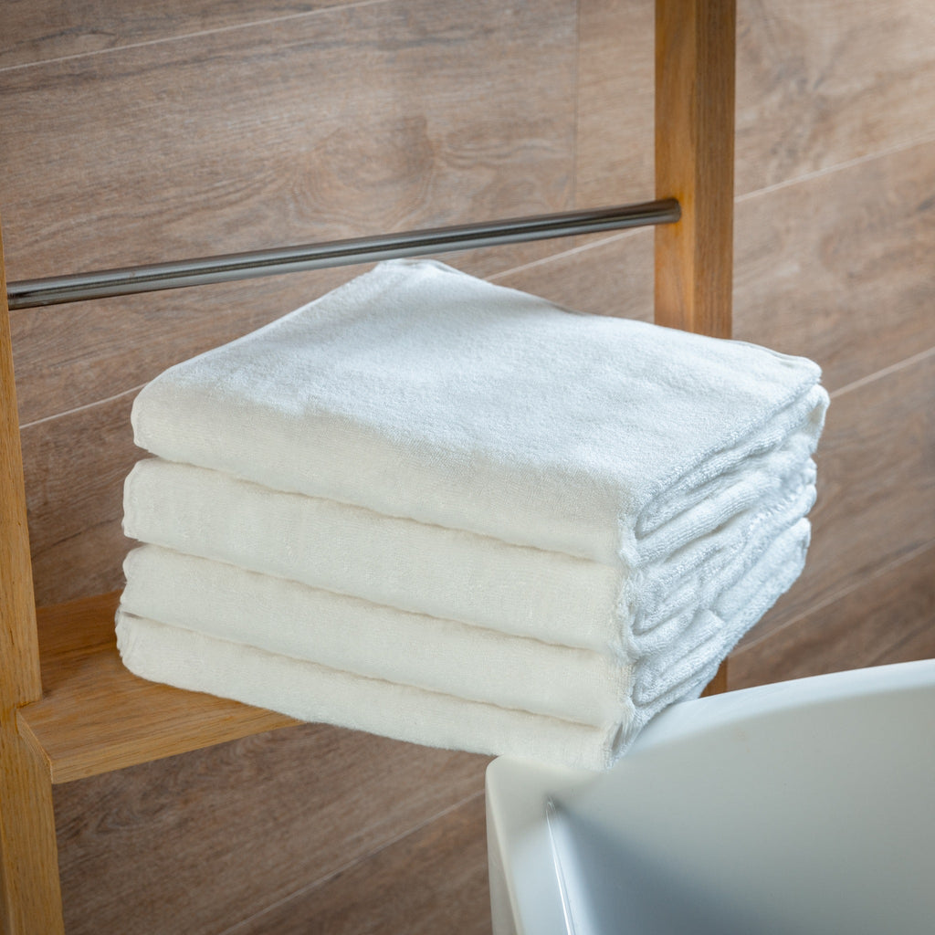 Stack of white towels on a wooden towel rack against a tiled wall.