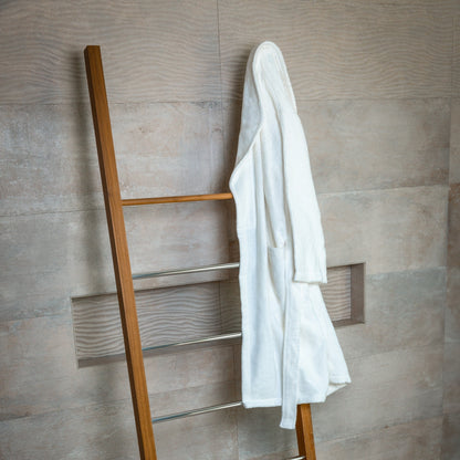 Wooden towel rack with a white robe against a tiled wall