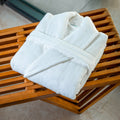 White bathrobe folded on a wooden bench