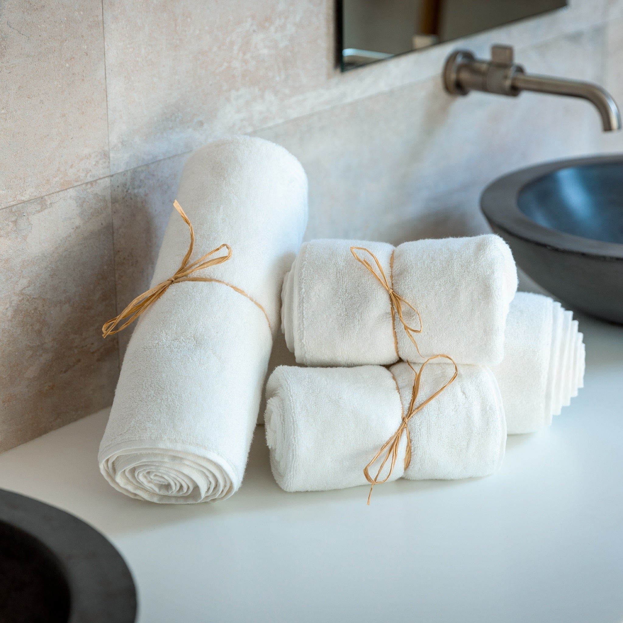 Stack of white towels tied with twine on a bathroom counter.