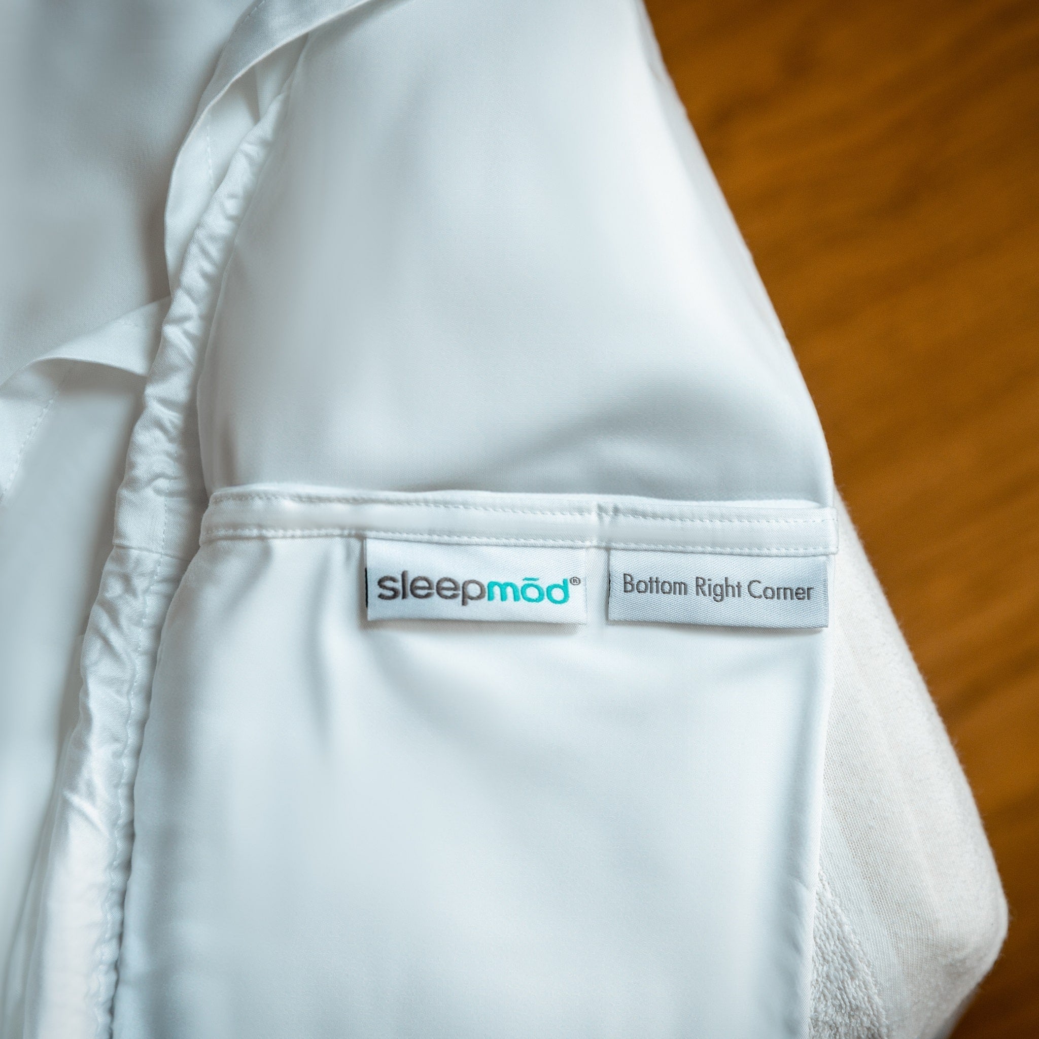 White fitted sheet with 'sleepmod' label on a mattress.