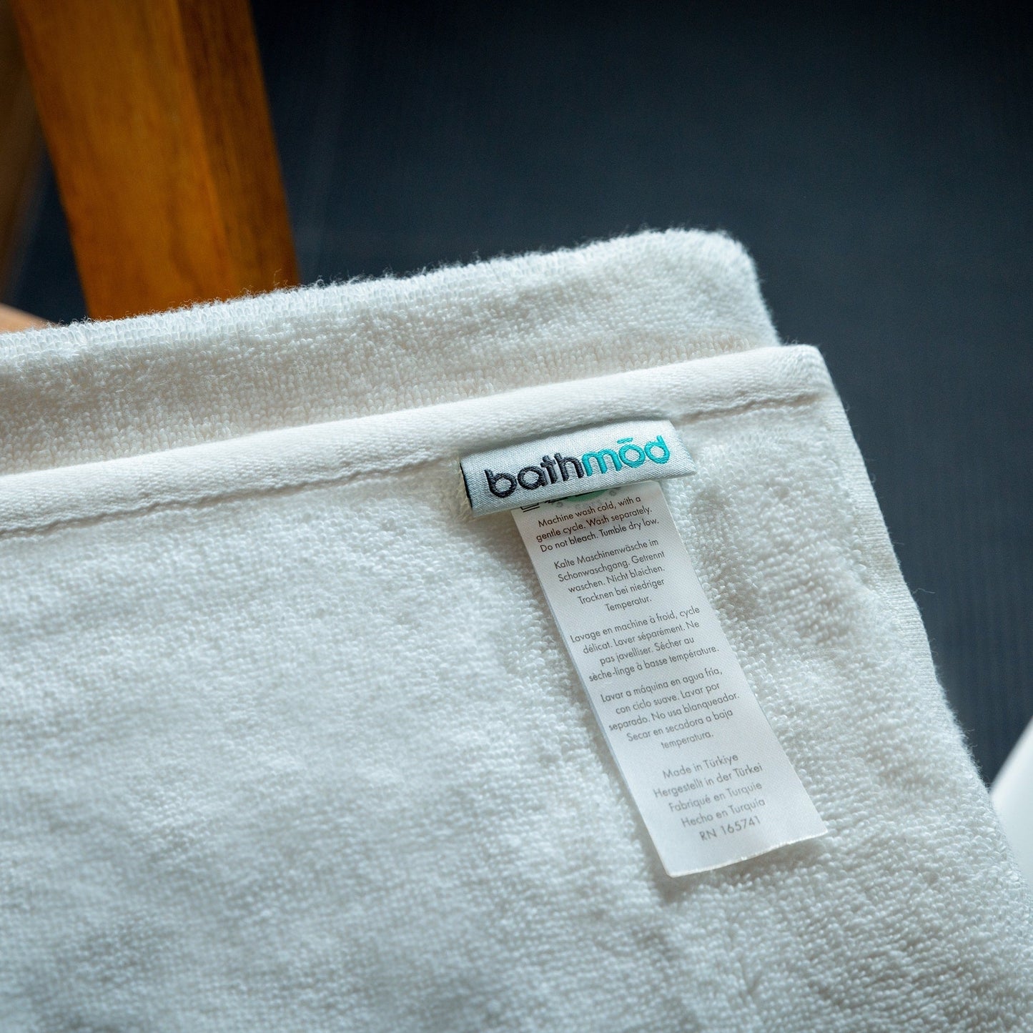 Close-up of a bath towel with a 'bathmod' label on a dark background