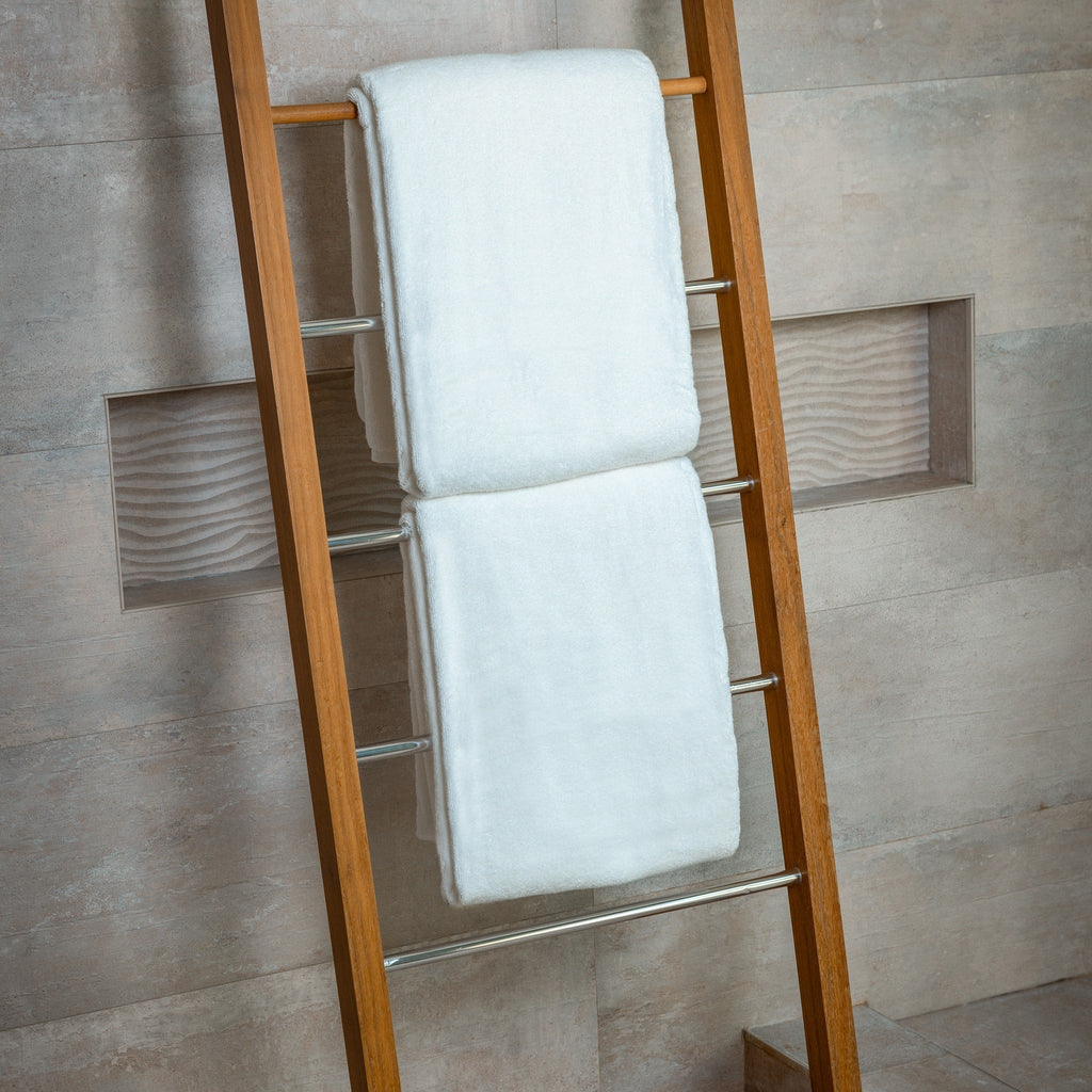 Wooden towel ladder with white towels against a tiled wall
